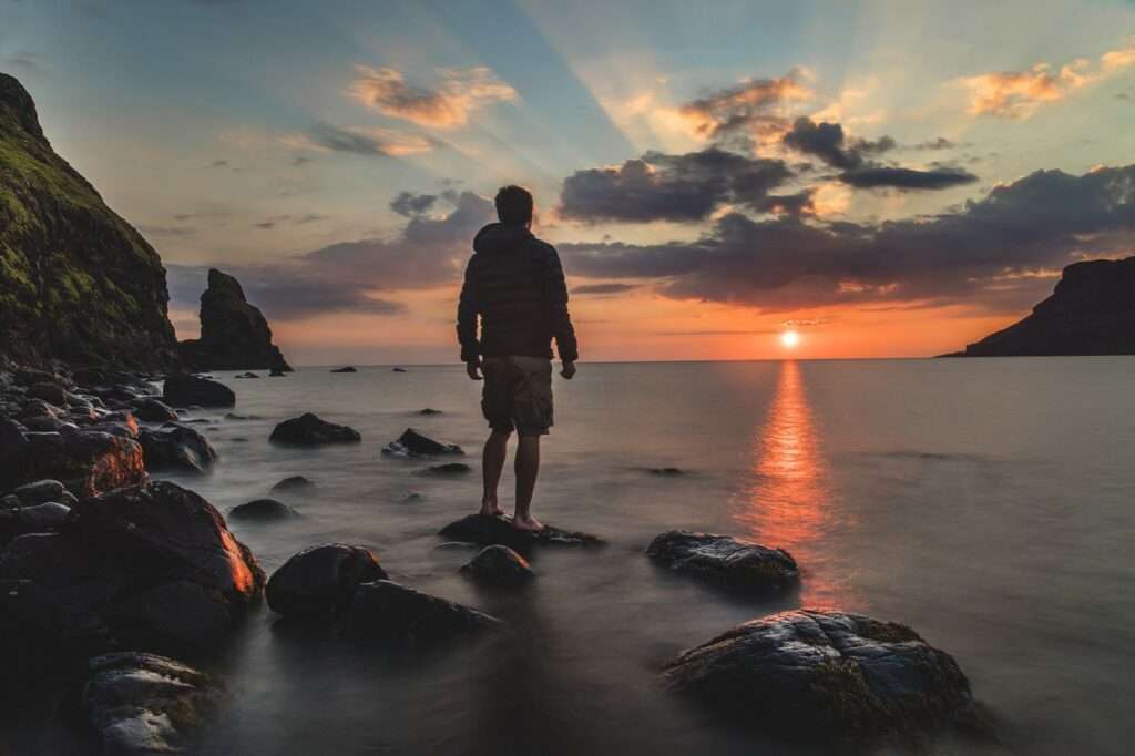 open mind - man standing on rock in front of ocean